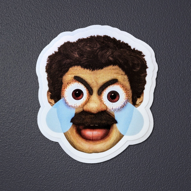 Kiszkiloszki sticker laying on a gray background. A head of the AAAaaa Guy from Kiszkiloszki animation. The man is screaming in a mix of anger and sadness, with an open mouth and comic-like blue tears streaming from his wide open brown eyes.