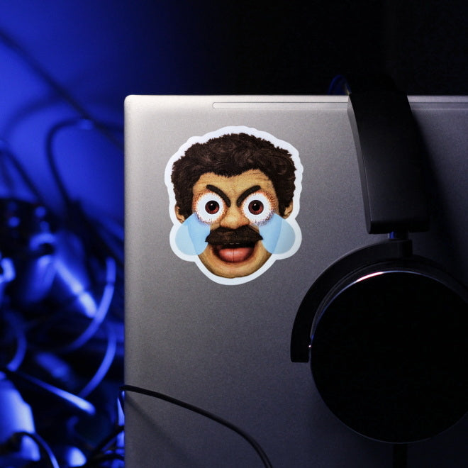 Kiszkiloszki sticker slapped on a silver laptop. A head of the AAAaaa Guy from Kiszkiloszki animation. The man is screaming in a mix of anger and sadness, with an open mouth and comic-like blue tears streaming from his wide open brown eyes.