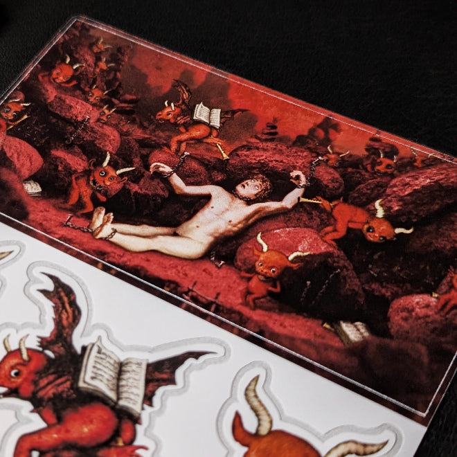 A close-up photo of a Kiszkiloszki sticker sheet. The stickers include designs such as cute little red devils dancing and playing trumpets with their butts, alongside a man in hell experiencing torment.