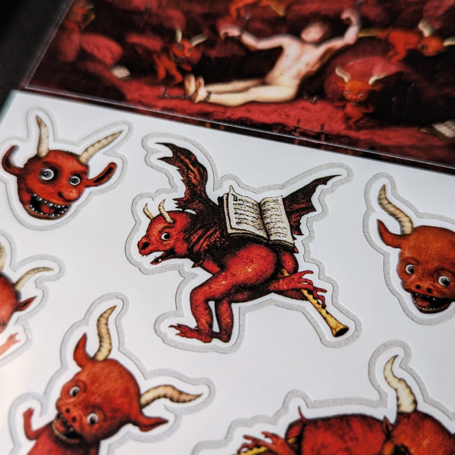 A close-up photo of a Kiszkiloszki sticker sheet. The stickers include designs such as cute little red devils dancing and playing trumpets with their butts.